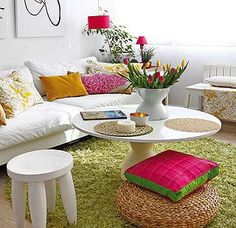 a living room filled with lots of white furniture and colorful pillows on top of it