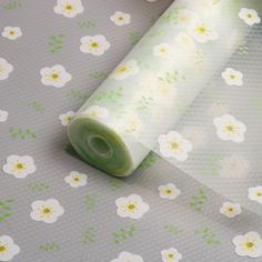 a roll of toilet paper sitting on top of a flowered wallpaper covered in green and white flowers