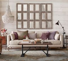 a living room with couches, chairs and mirrors on the wall in front of them