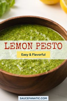 a wooden bowl filled with pesto next to lemons