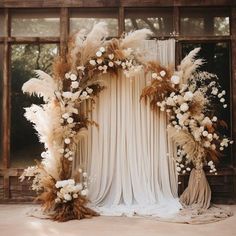 a wedding arch with flowers and feathers on it