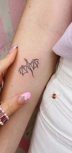 a woman's arm with a tattoo on it that has a bat design on it