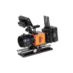 an orange and black camera sitting on top of a tripod next to a white background