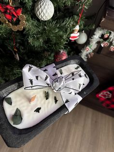 a present wrapped in white paper sitting on top of a tray next to a christmas tree