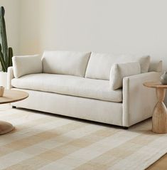 a white couch sitting on top of a wooden table next to a potted plant