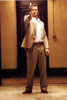 a man in a suit and tie holding a cell phone up to his ear while standing in an elevator