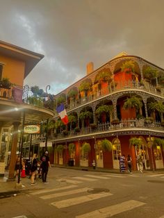 an old building with balconies on the second story and people walking down the street