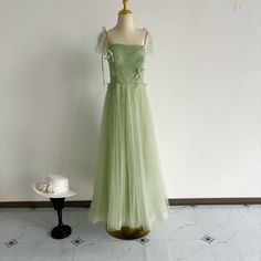 a dress on display in front of a white wall with a small hat sitting next to it