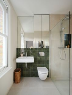 a bathroom with a toilet, sink and shower in it's corner next to a window