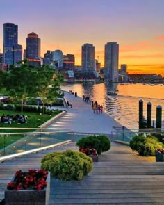 the sun is setting in front of a cityscape with boats docked on the water