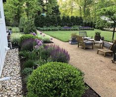 an outdoor patio area with chairs and graveled path leading to the back yard, surrounded by lush greenery