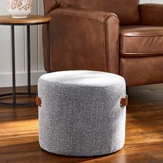 a living room with a brown leather chair and footstool on the wooden floor