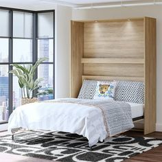 a bed with a headboard built into the side of it in front of a window