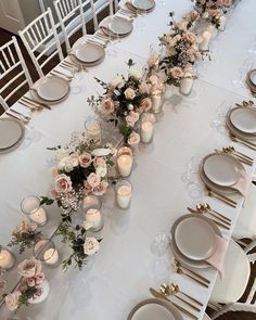 a long table is set with white and pink flowers, candles and place settings for dinner