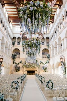 an indoor wedding venue with white chairs and chandelier