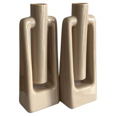 two cream colored vases sitting side by side on a white background, one is shaped like a rectangle