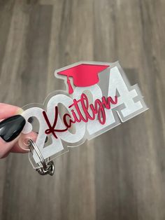 a hand holding a keychain with the word kentucky on it and a graduation cap