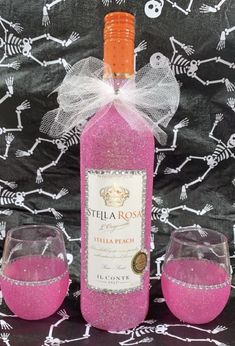 a bottle of pink wine with two glasses next to it on a black tablecloth