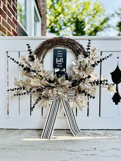 a wreath with black and white decorations on the side of a building that has a sign hanging from it