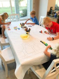 three children are sitting at a table playing with legos and building their own cars