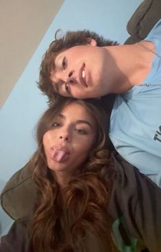 two people laying on top of each other with their tongue out and one person making a funny face