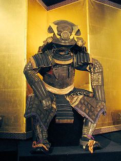 an elaborately dressed samurai sitting in front of a golden box with other items around it