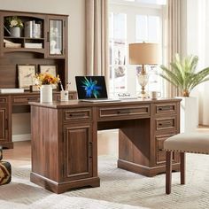 a desk with a laptop on it in front of a chair and bookshelf