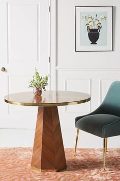 a dining room table with two chairs in front of it and a painting on the wall