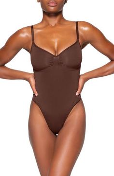 Updated for an even better fit, this fan-fave bodysuit from Kim Kardashian's SKIMS offers extra compression at the core and waist to cinch your natural shape. Strategically placed lines flatter your bust and provide definition, and the low back makes it easy to wear under a variety of outfits. Snap closure Scoop neck Adjustable straps Cotton-lined gusset 82% nylon, 18% spandex Machine wash, tumble dry Imported Kim Kardashian, Cocoa, Sculpting Bodysuit, Teddy Bodysuit, Teddy Lingerie, Different Dresses, Creative Direction, Shapewear, Snap Closure