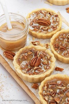 four pecan pies sitting on top of a cutting board next to a jar of peanut butter