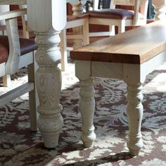 a wooden bench sitting in the middle of a living room next to a table and chairs