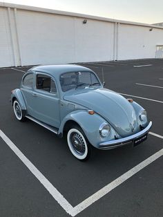 an old blue vw bug parked in a parking lot