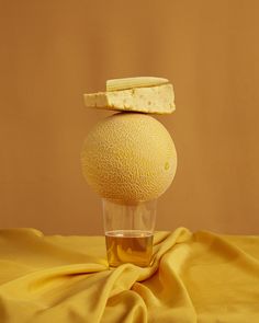 a yellow object sitting on top of a glass filled with liquid next to a piece of bread