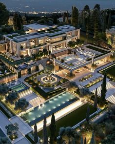 an aerial view of a mansion at night with lights shining on the building and pool area