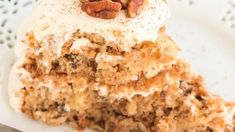 a piece of carrot cake on a white plate with a fork and pecans in the middle