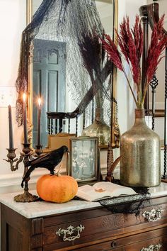 an old dresser is decorated with halloween decorations and candles for the holiday season, including pumpkins