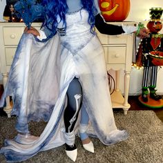 a woman dressed in costume standing next to a table with pumpkins on top of it