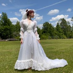 a woman in a wedding dress standing on the grass