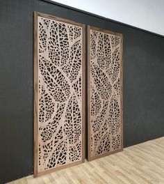 two wooden doors with intricate designs on them in a room next to a black wall