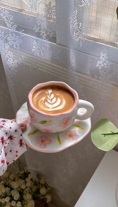 a cup of coffee is sitting on a saucer in front of a flower pot