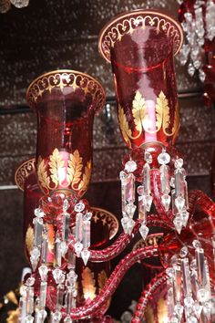 a red chandelier hanging from the ceiling in a room filled with glass vases