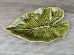 a green leaf shaped dish sitting on top of a wooden table