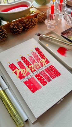 a christmas card with the word happy written in gold foil on it next to some pine cones and other holiday decorations