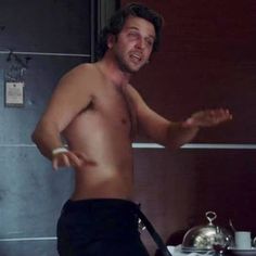 a man without a shirt standing in front of a sink with his hands out to the side