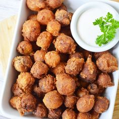 a white bowl filled with tater tots next to a small bowl of ranch dressing