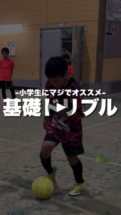 a young boy kicking a soccer ball on top of a gym floor in front of other children