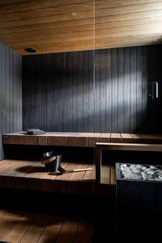 an empty sauna with wooden floors and dark wood paneling on the wall behind it