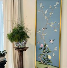 a blue wall with white flowers and birds painted on it next to a planter