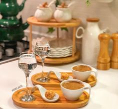 two glasses of wine and some food on a wooden tray in front of other dishes