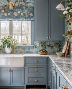 a kitchen with blue cabinets and floral wallpaper on the walls, along with a white sink